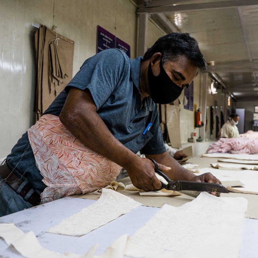 Skilled textile worker in India cutting fabric on a production table — representing Zeddwork Studio’s tailored manufacturing solutions for clothing brands worldwide.