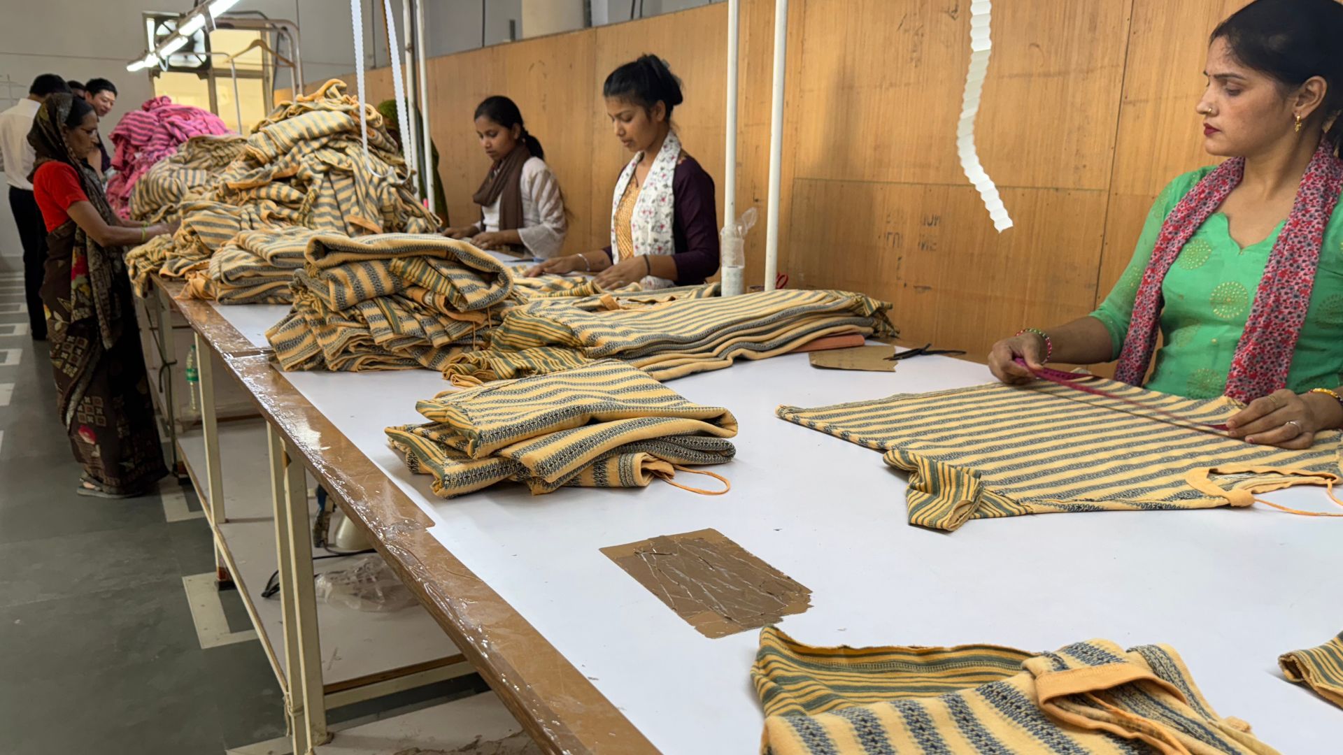 ladies in indian factory inspecting hoodies in packing table of a garment factory